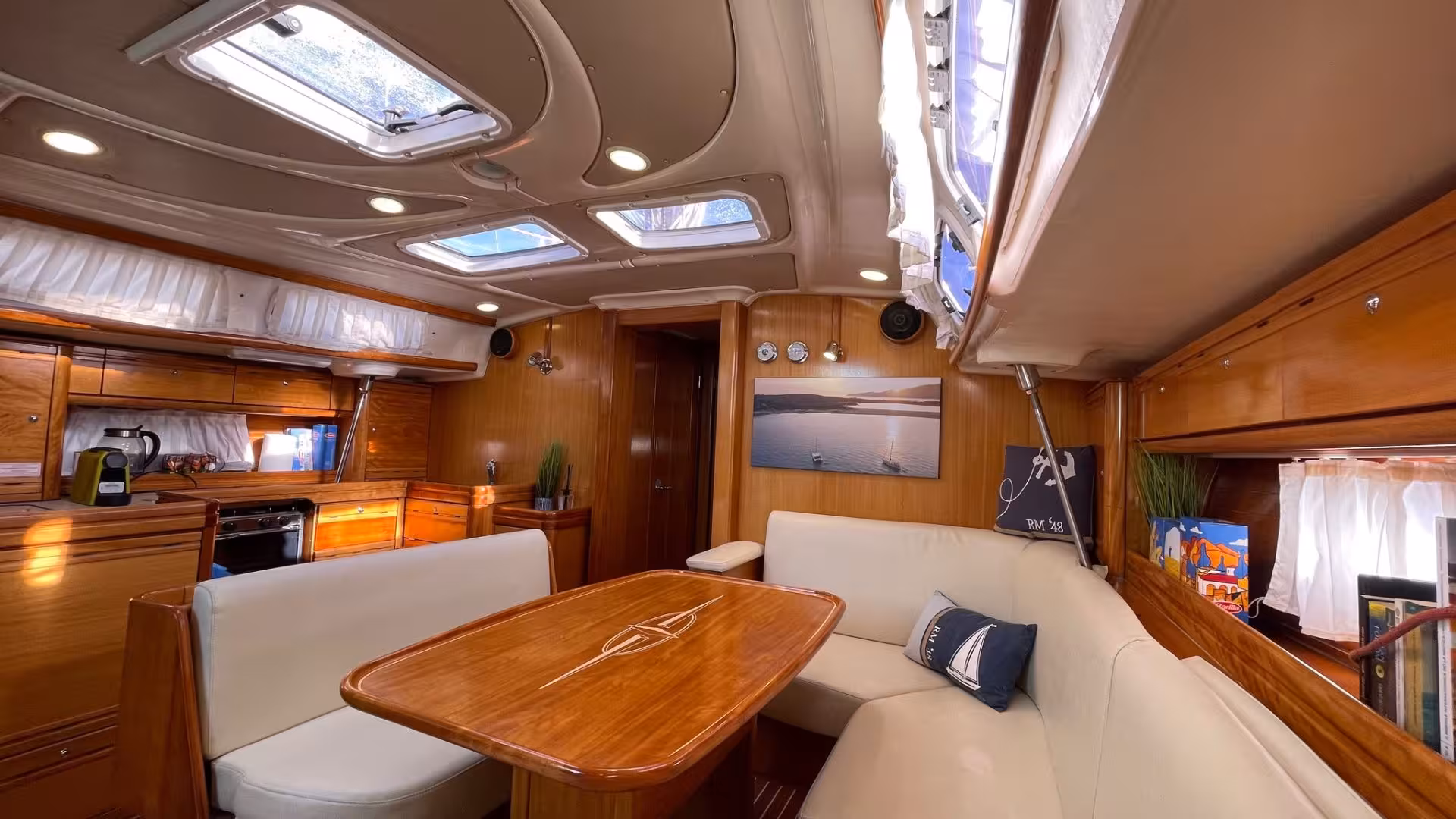Luxurious interior of a sailing boat, featuring a wood-finished cabin with seating, part of the Cagliari Mari Pintau tour.