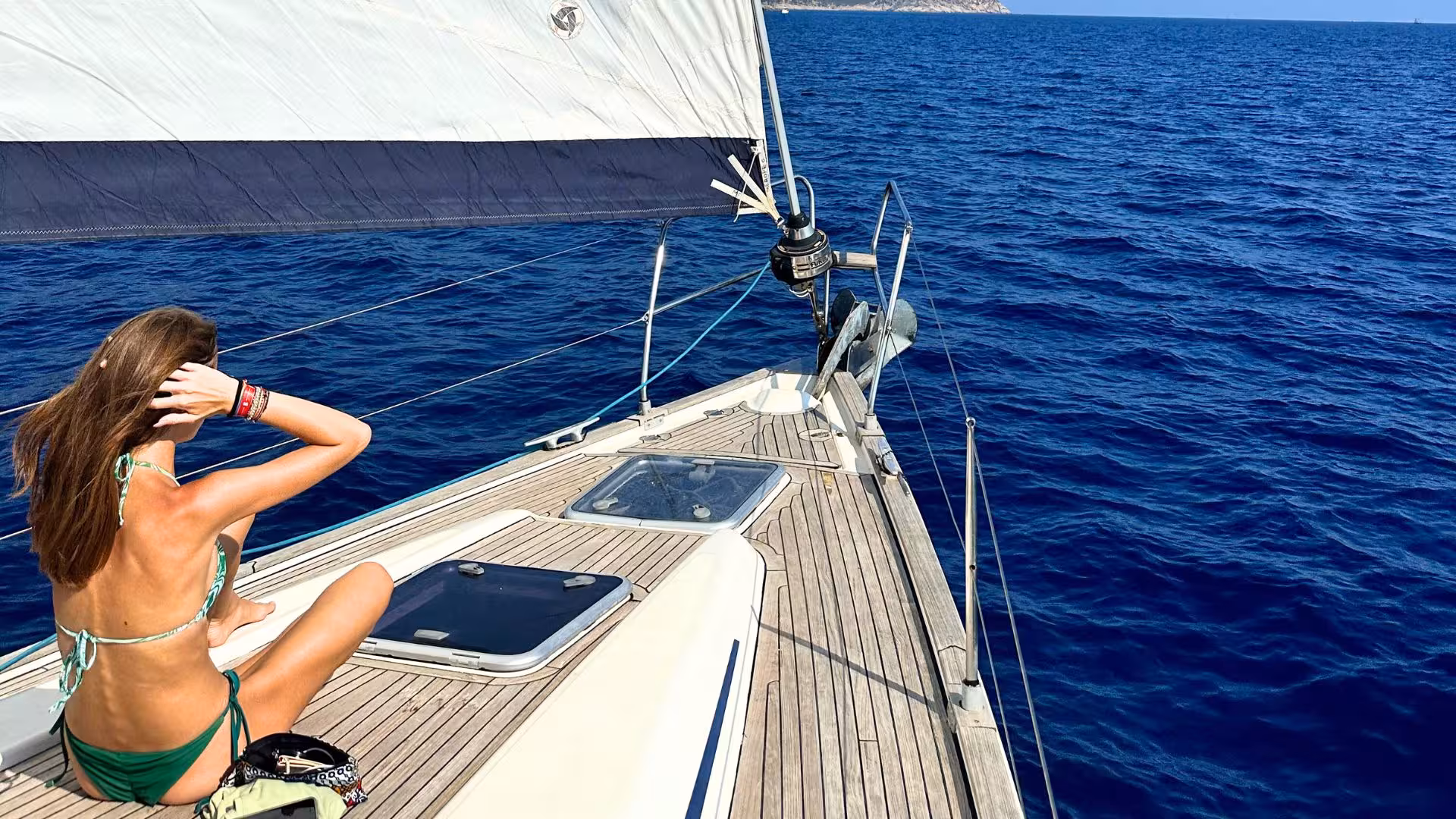 Woman relaxing on the deck of a sailing boat amid the stunning blue waters off the coast of Cagliari.
