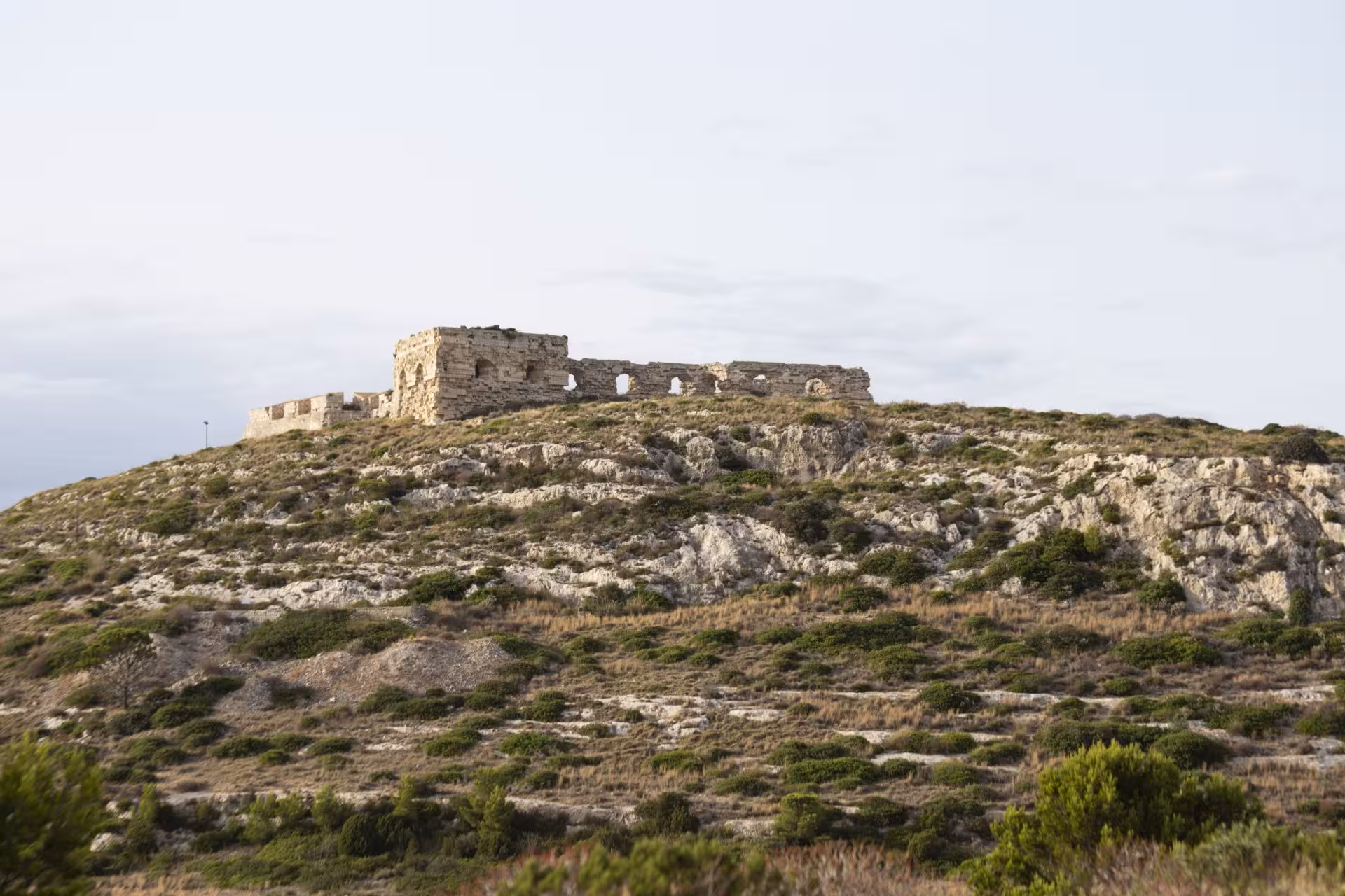 Ruins of an ancient fort atop Sant'Elia hill, offering panoramic views of the scenic Sardinian landscape.