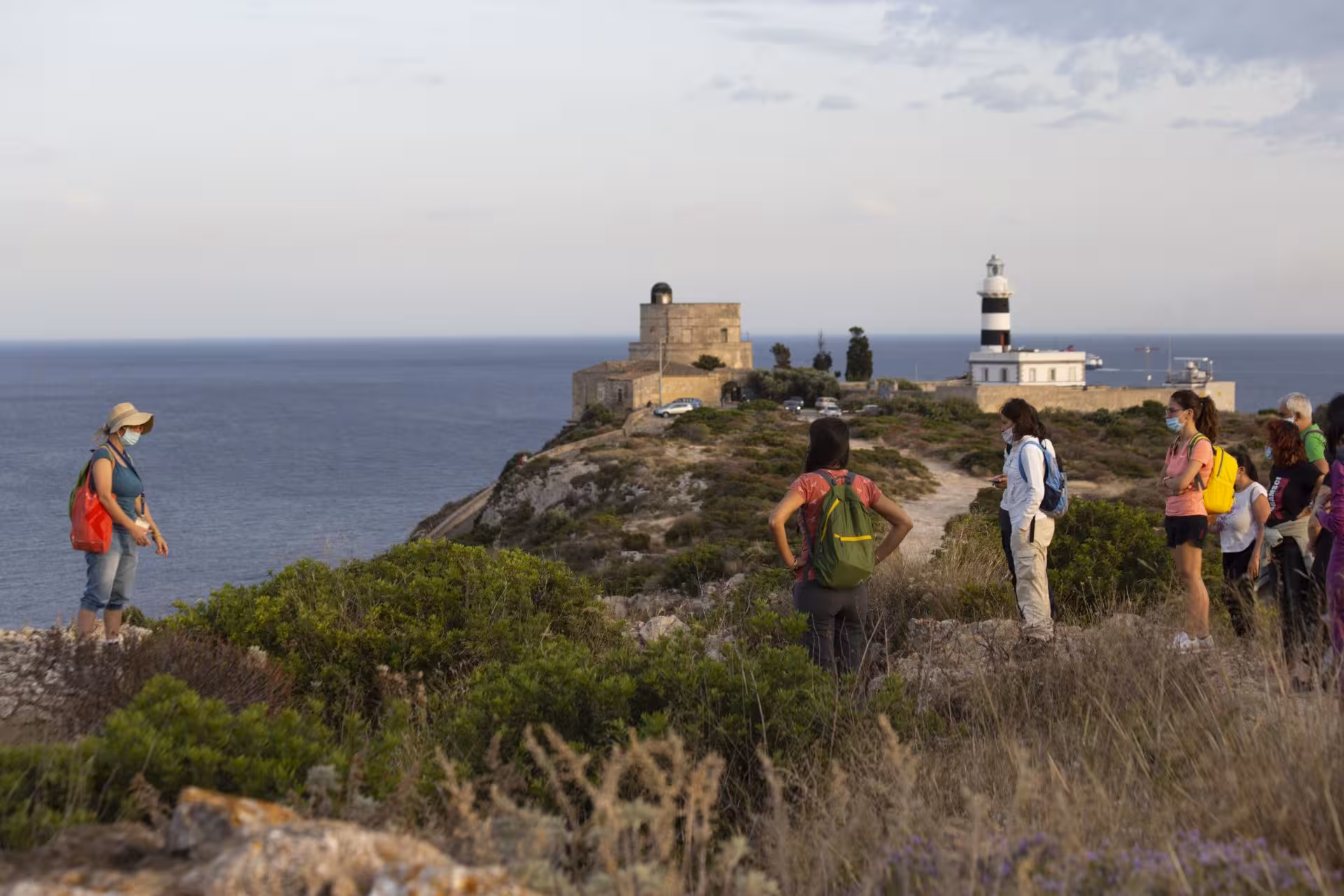 Group trekking on Sant'Elia hill in Cagliari with stunning views of the lighthouse and Mediterranean Sea.
