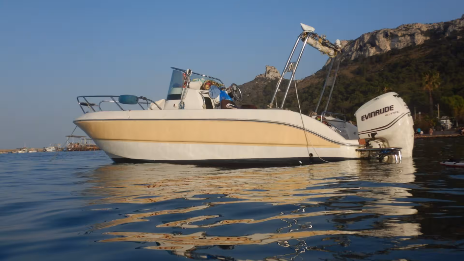 A sleek tour boat ready for a Cagliari snorkeling adventure, set against a backdrop of scenic cliffs.