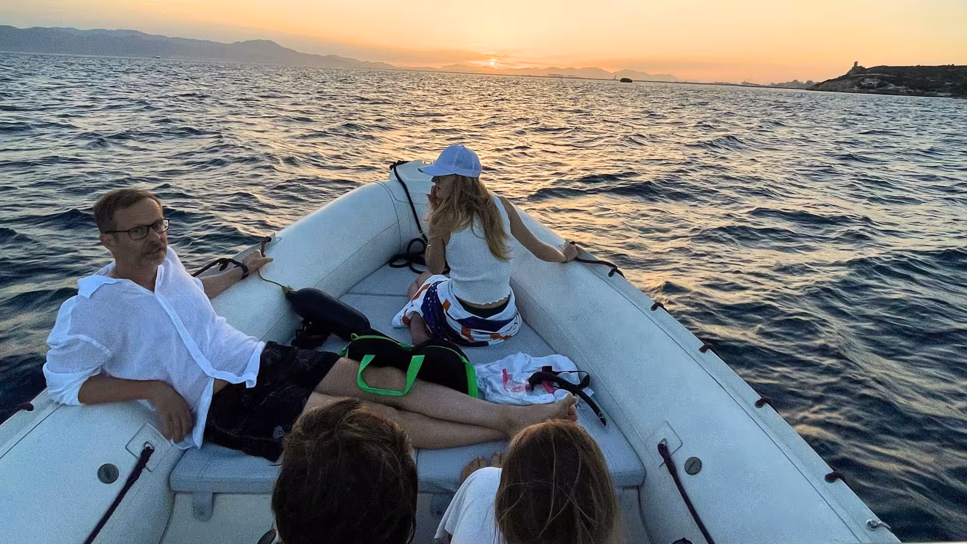 Relaxing sunset dinghy tour off Cagliari with views of the sea and mountains in the background.