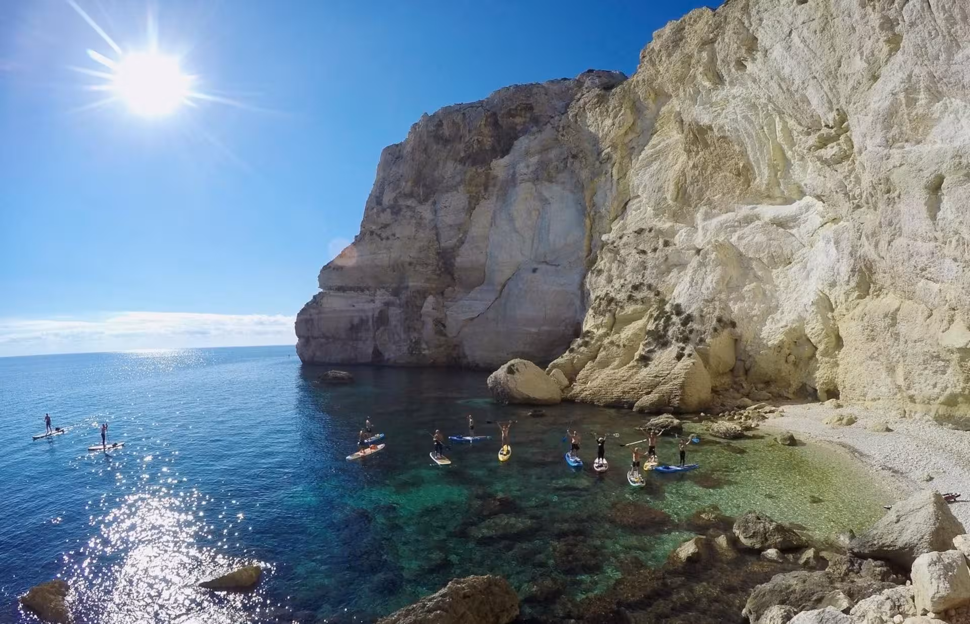 Group of paddleboarders exploring the stunning cliffs and waters of Sella del Diavolo in Cagliari.