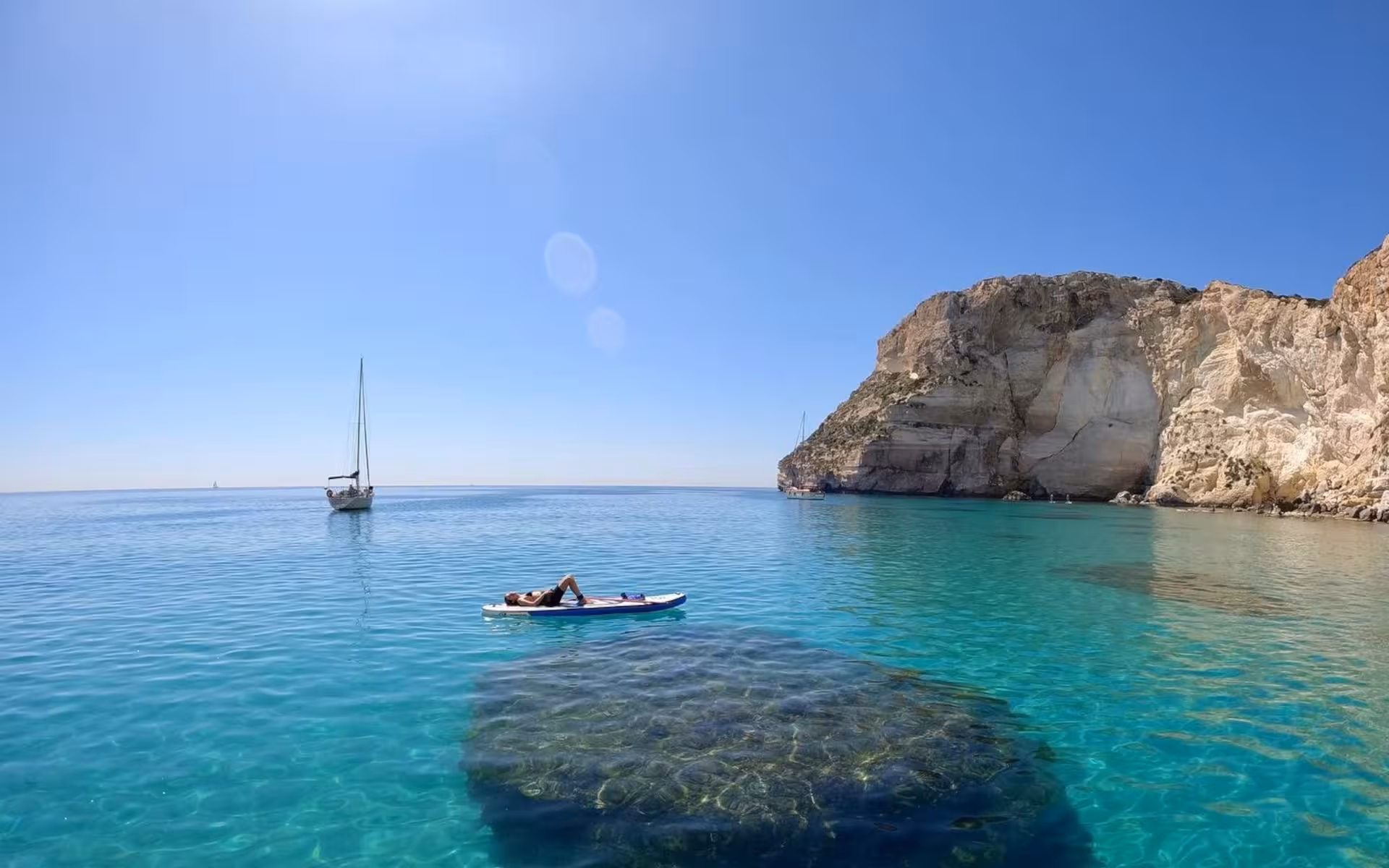 Relaxing on a paddleboard near Cagliari's stunning Sella del Diavolo with a scenic view of turquoise waters and cliffs.