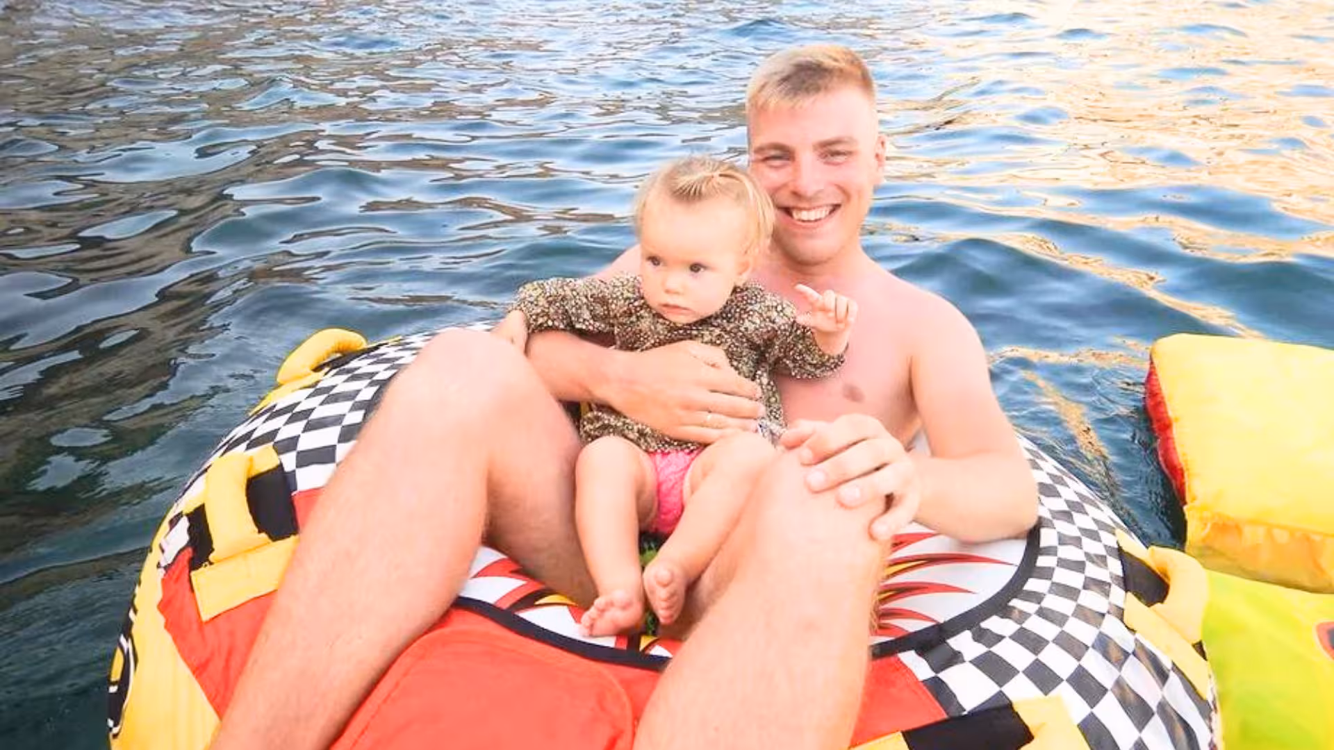Father and child enjoying a fun water ride on an inflatable tube in Golfo degli Angeli, Cagliari experience.