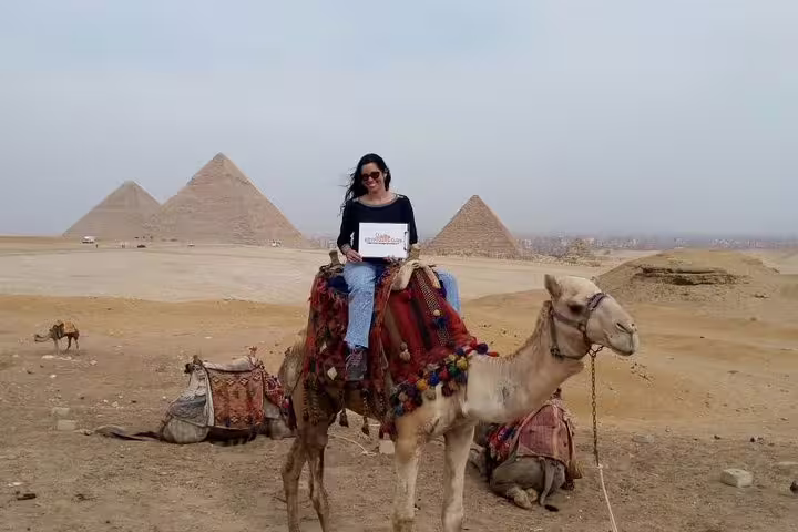 Cairo Airport layover to Giza Pyramids private tour, traveler on camel with panoramic pyramid views