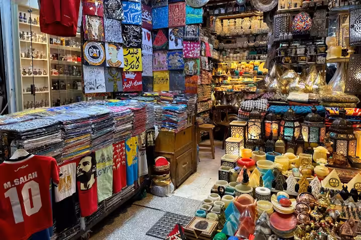 Colorful Cairo bazaar stall selling Egypt souvenirs, lanterns, t-shirts with M. Salah jersey and pyramids decor