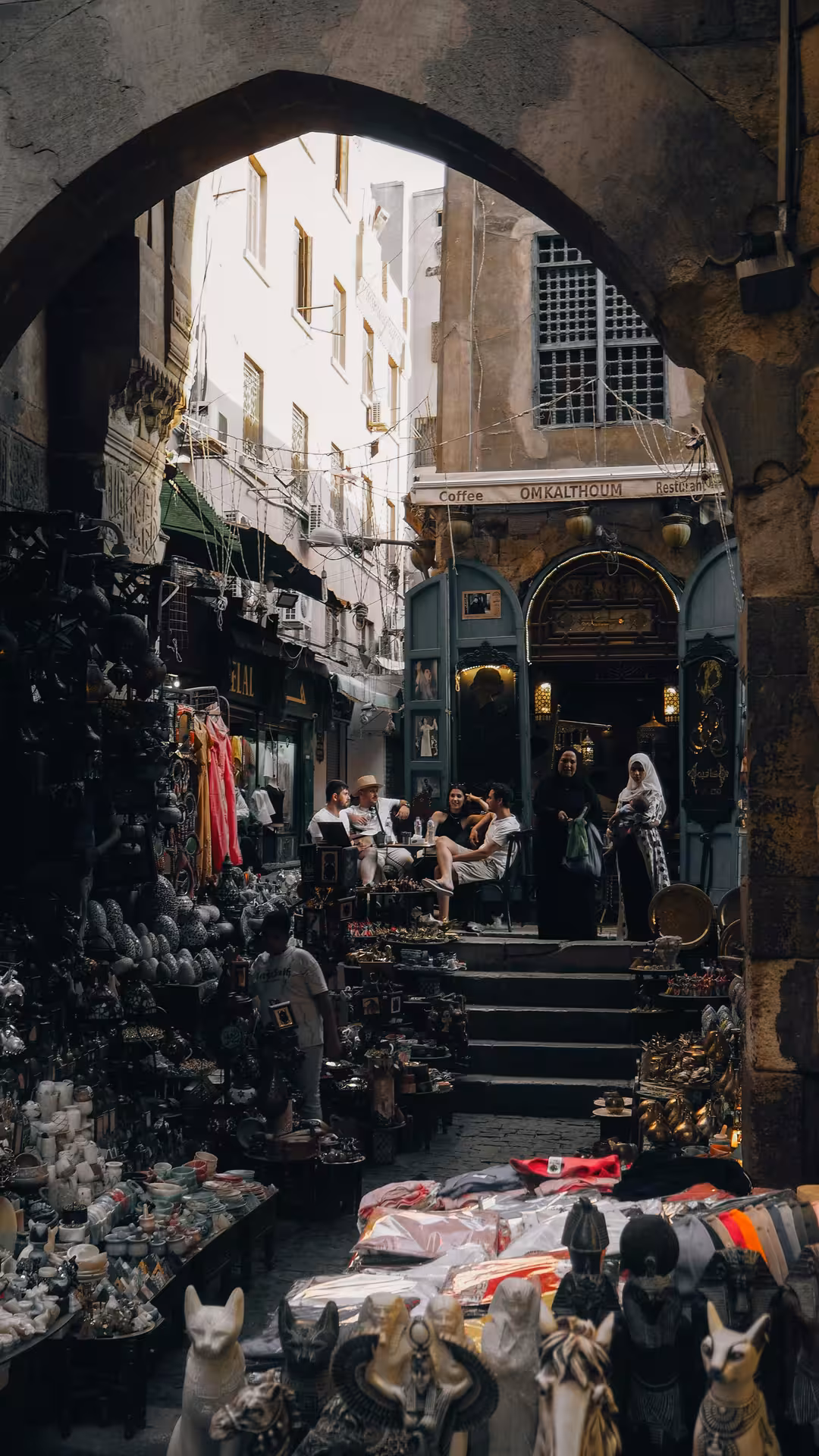 Bustling Khan el-Khalili bazaar alley with souvenir stalls and Om Kalthoum café in Cairo