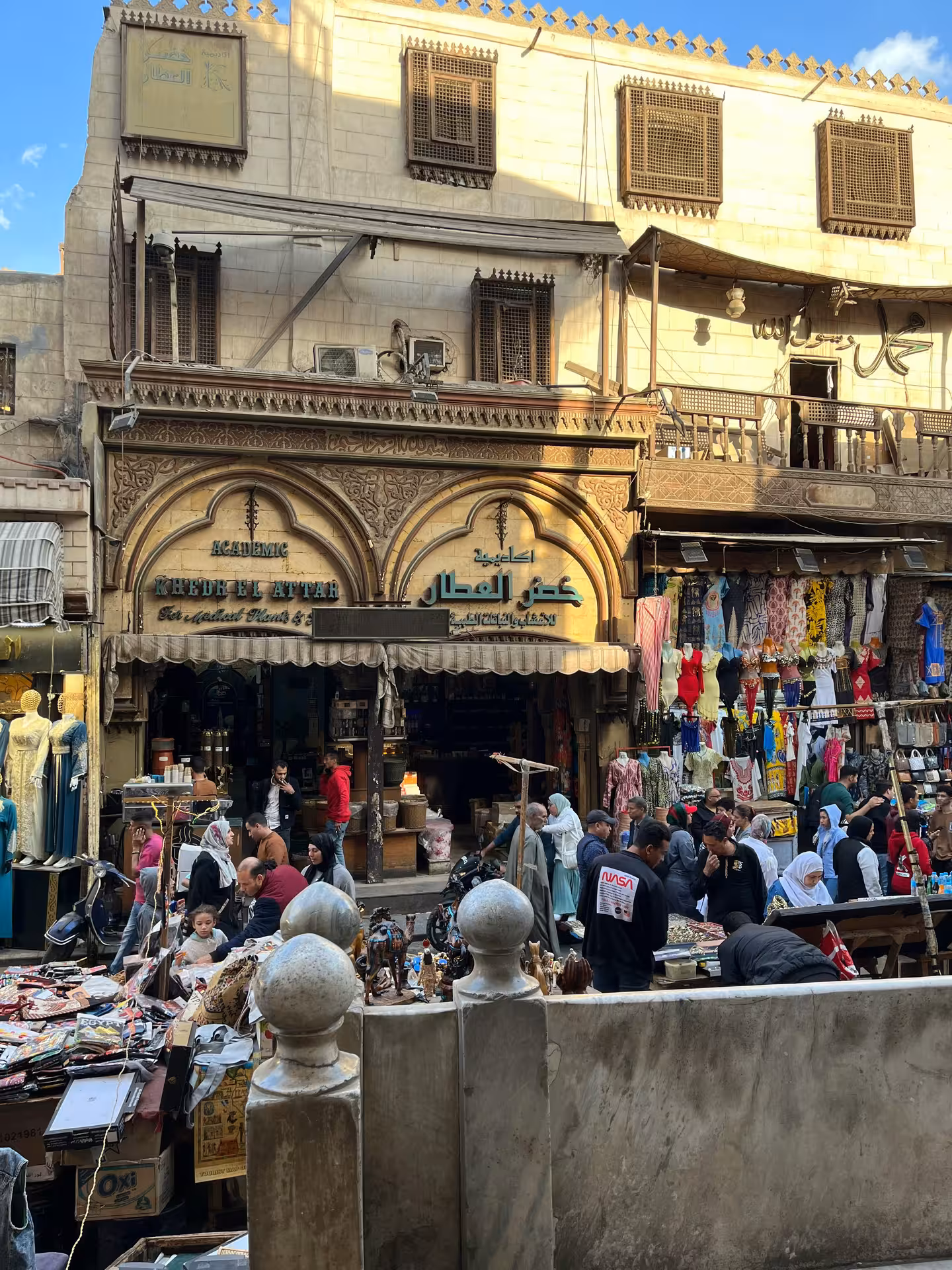 Busy Cairo bazaar with shoppers outside Khedr El Attar shop, traditional Islamic architecture, Khan el-Khalili market