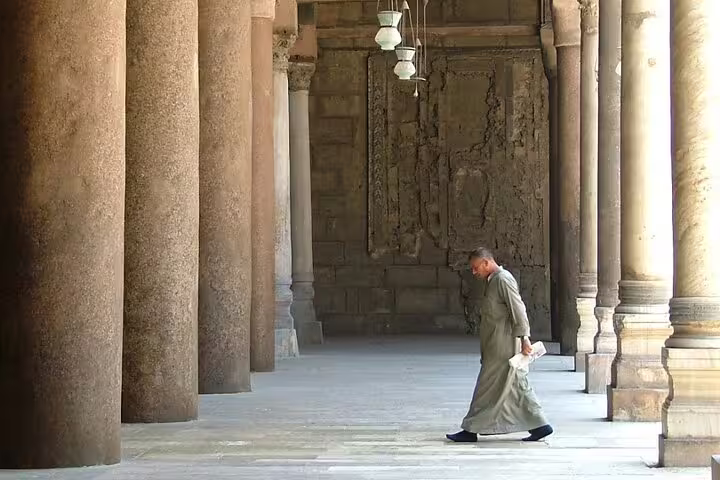 Historic stone colonnade at Cairo Citadel with visitor walking, on a day trip combining Giza and Coptic Cairo