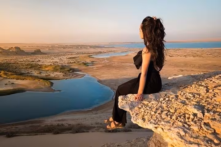 Traveler overlooking Fayoum Magic Lake and desert dunes on Cairo day trip, sunset panorama and sandboarding views