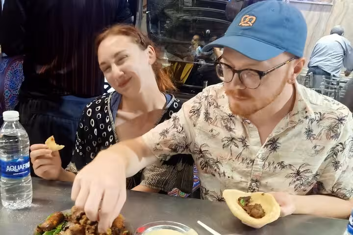 Travelers tasting Egyptian street food at a Cairo market stall during a private walking food tour