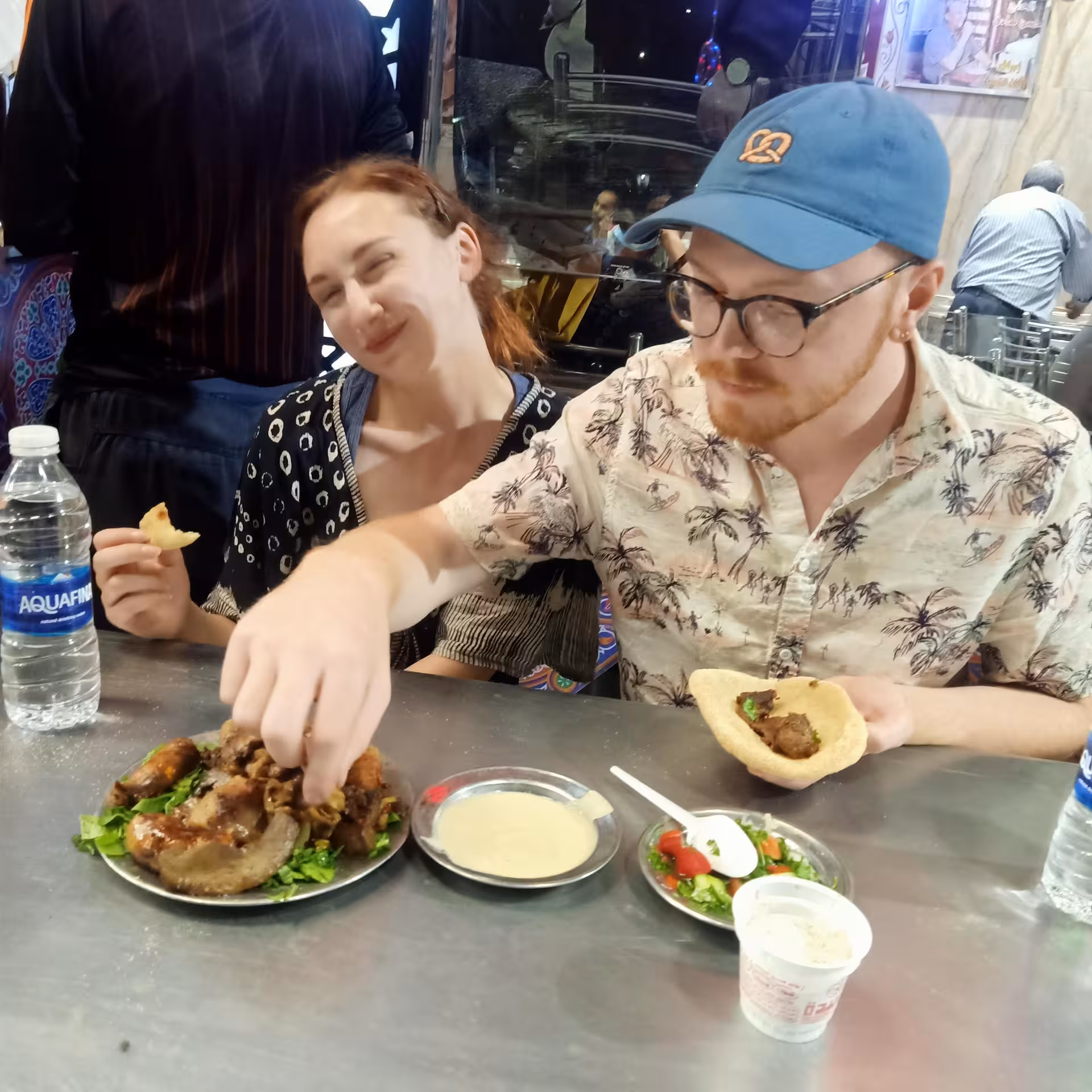 Guests taste Egyptian street food at a Cairo private food tour stop, sharing mezze and pita at a local eatery