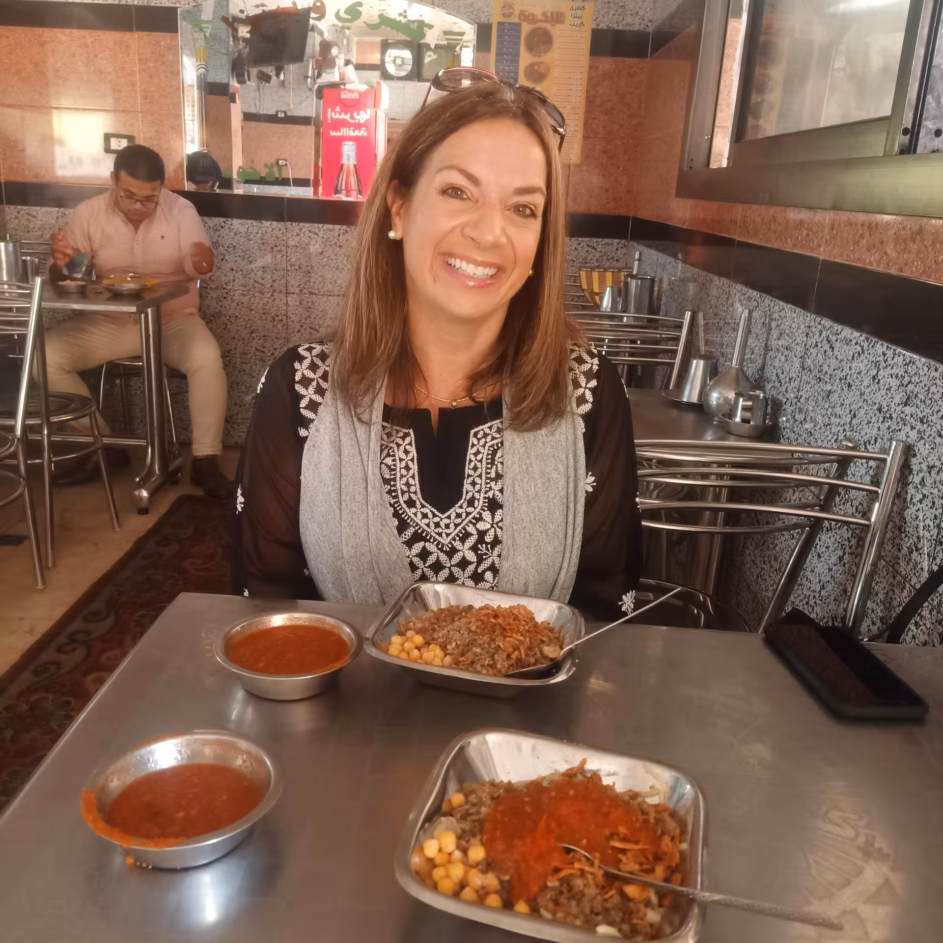 Guest enjoying koshari and spicy tomato sauce at local eatery on private Cairo food tour walking experience