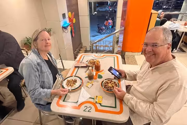 Guests enjoying koshary and drinks at a local Cairo eatery on a private Cairo food tour walking experience