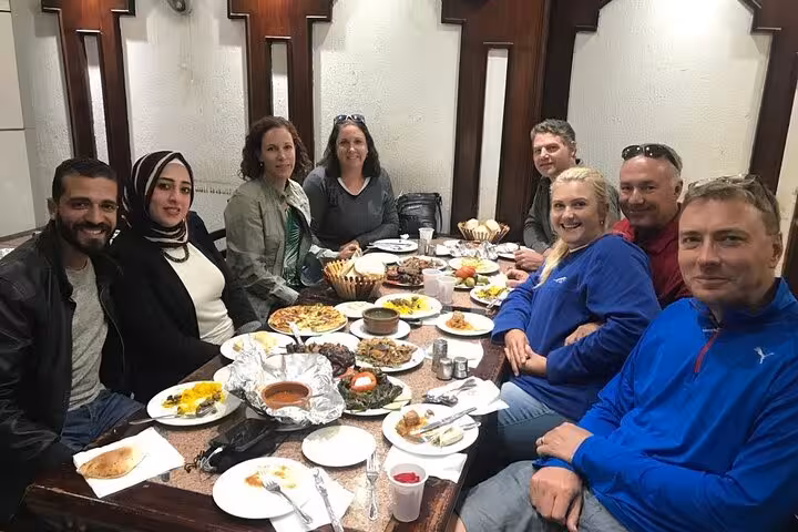 Travelers dining with a local guide at an Egyptian restaurant, tasting classic dishes on a Cairo food tour
