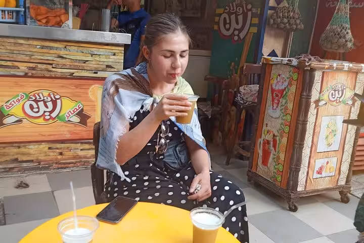 Traveler sipping fresh sugarcane juice at a Cairo street stall during a private food tour and walking tour