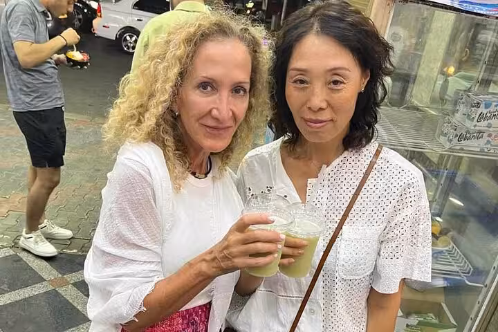 Two travelers tasting sugarcane juice at a Cairo street stall on a private food tour and funny walking tour