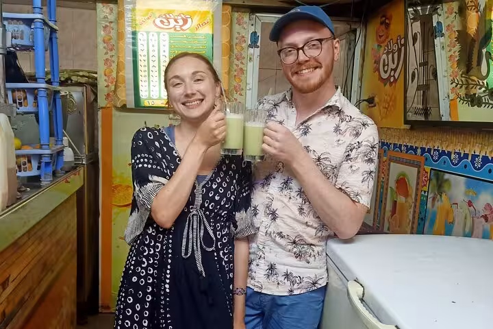 Happy travelers toast fresh sugarcane juice on a private Cairo food tour and funny walking street tour