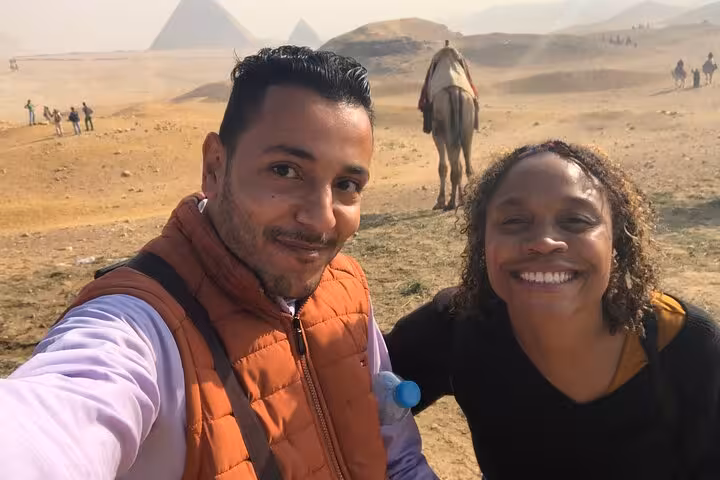 Private tour guide and traveler selfie in Giza desert with camel and pyramids, Cairo and Giza sightseeing