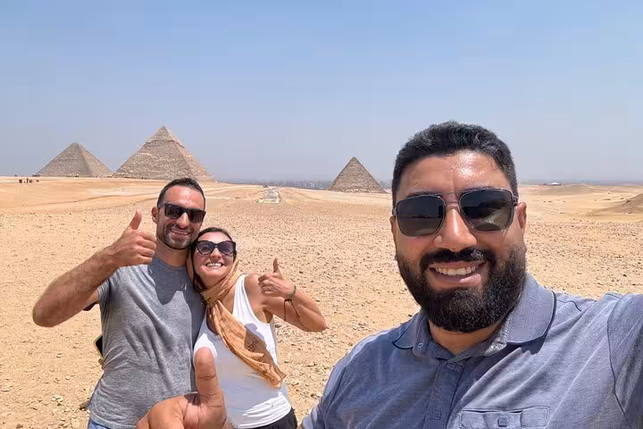 Happy travelers with guide at Giza Pyramids near Cairo, private tour photo with desert panorama