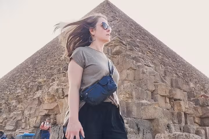 Traveler posing by the Great Pyramid of Giza during a Cairo private trip, showcasing massive stone blocks at sunset