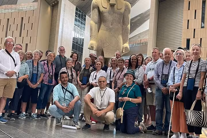Tour group inside the Grand Egyptian Museum Cairo with giant pharaoh statue, guided private visit after Giza Pyramids