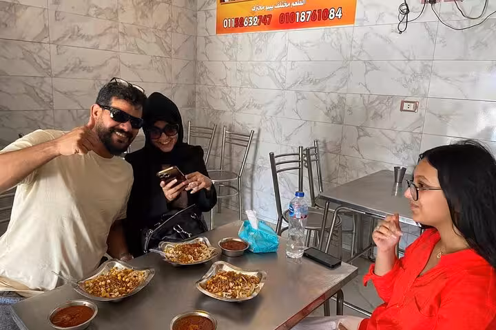 Friends share koshary lunch in Cairo restaurant after Khan el Khalili Market shopping on guided tour