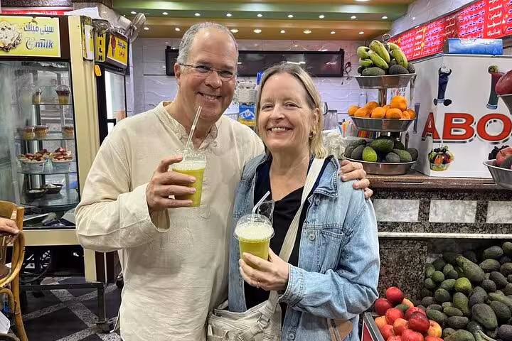 Tour guests sip fresh sugarcane juice at a Cairo Khan el Khalili Market stop during guided shopping tour