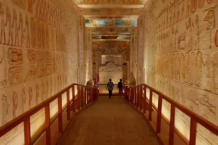 Visitors walking through an ancient Egyptian tomb corridor with hieroglyphs, Cairo to Luxor 5D4N package