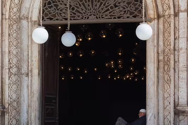 Historic Cairo mosque entrance with carved stone arch and hanging lamps, featured on Citadel, Bazaar and Mosques tour