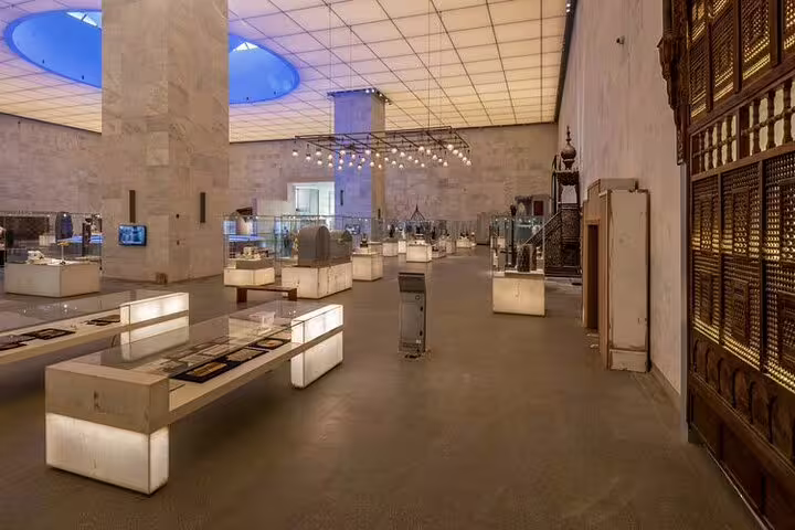 National Museum of Egyptian Civilization gallery in Cairo with illuminated artifact cases on guided tour