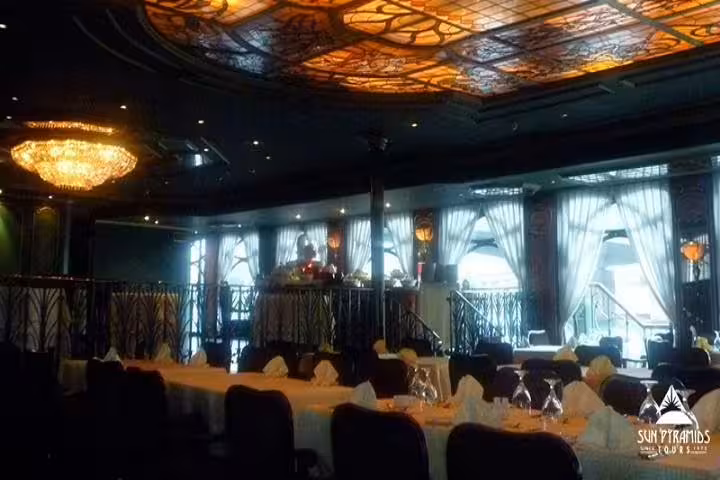 Elegant Cairo Nile dinner cruise lounge with chandelier lighting, set banquet tables, and live show stage