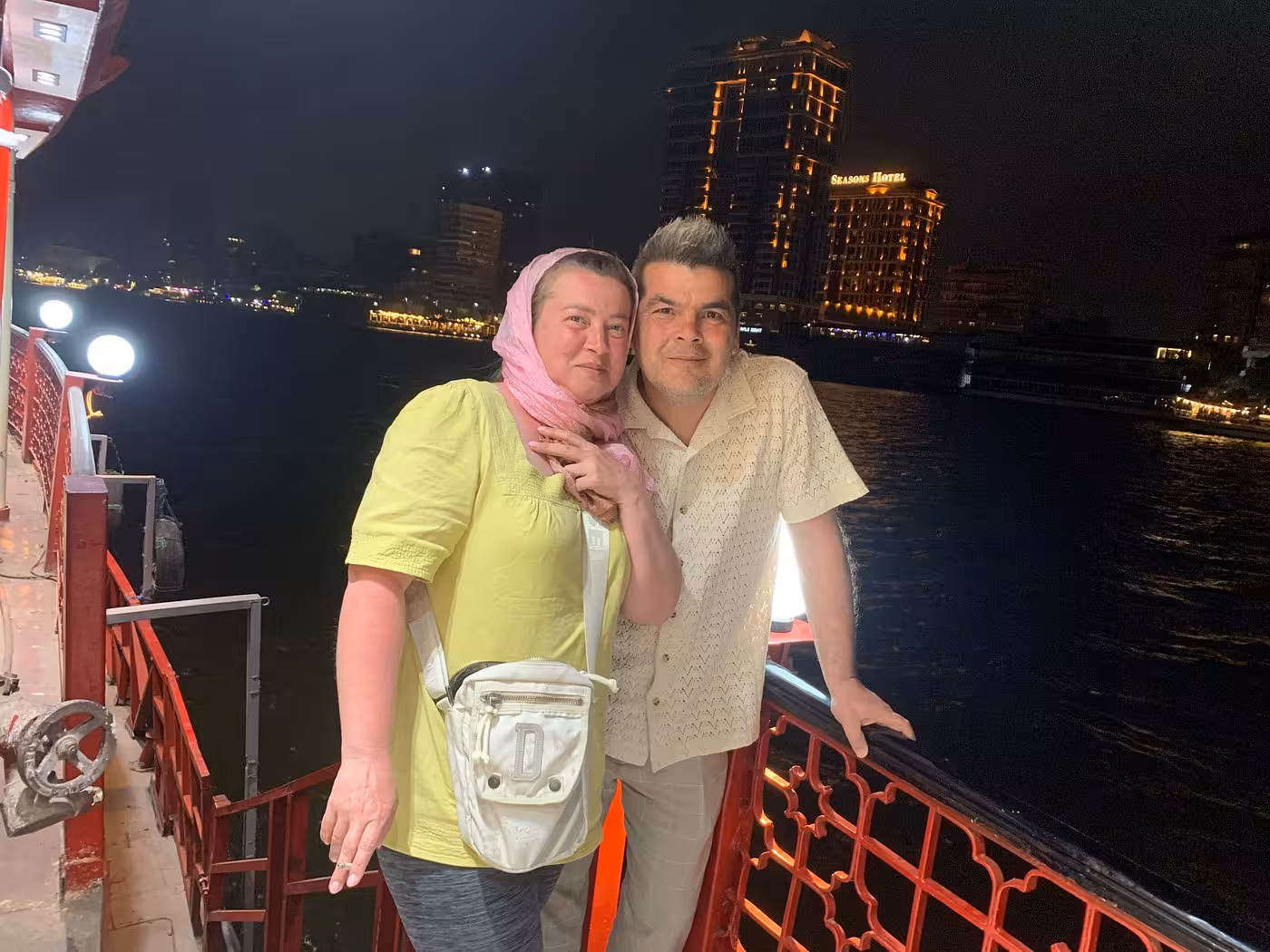Couple posing on deck at night on Cairo Nile dinner cruise, city lights and private transfer experience