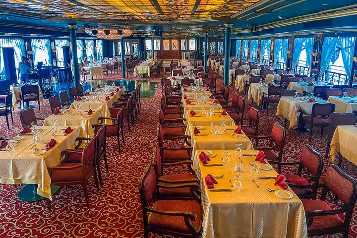 Elegant Cairo Nile dinner cruise dining hall with set tables, river-view windows, and evening ambiance
