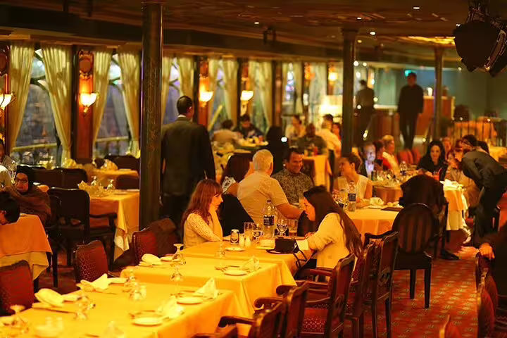 Elegant dining room on Cairo Nile dinner cruise with seated guests, warm lighting and panoramic river windows