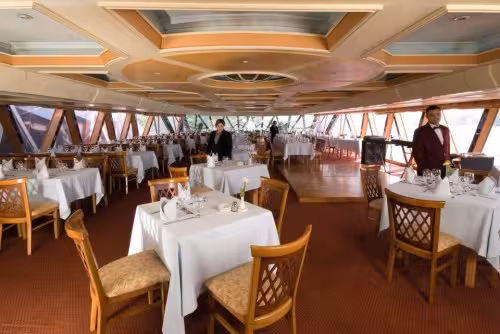 Elegant indoor restaurant on Cairo Nile dinner cruise, white-table dining before belly dancing and show