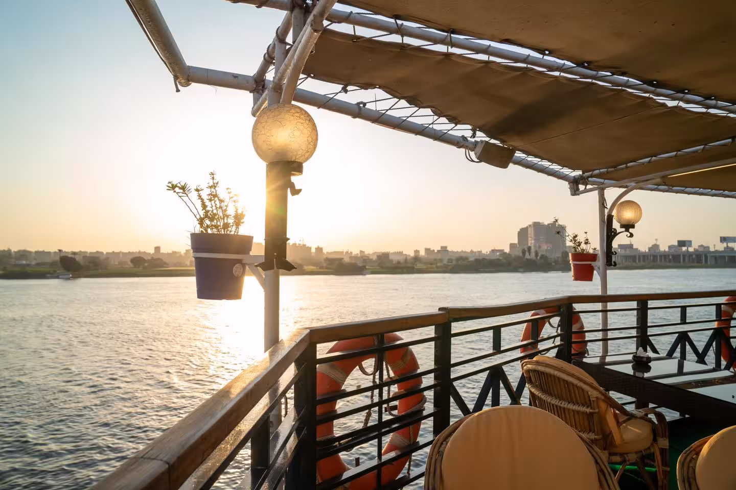 Sunset view from the deluxe Nile dinner cruise deck in Cairo, riverside skyline and outdoor seating area