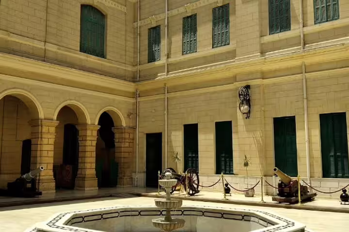 Courtyard of historic Cairo palace with arches and cannons, a stop on Al Moez Street night walking tour