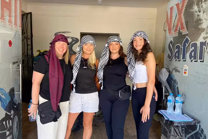 Group wearing keffiyeh scarves at Cairo quad bike safari base before camel ride, lunch and shopping tour