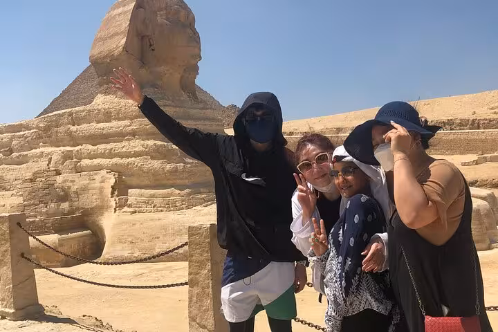 Travelers posing by the Great Sphinx of Giza on Cairo 2-day tour featuring pyramids, Citadel and bazaar