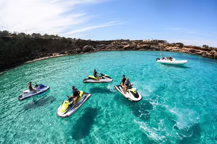 Group guided jet ski tour in crystal-clear waters near Cala Comte, Ibiza, with support boat nearby
