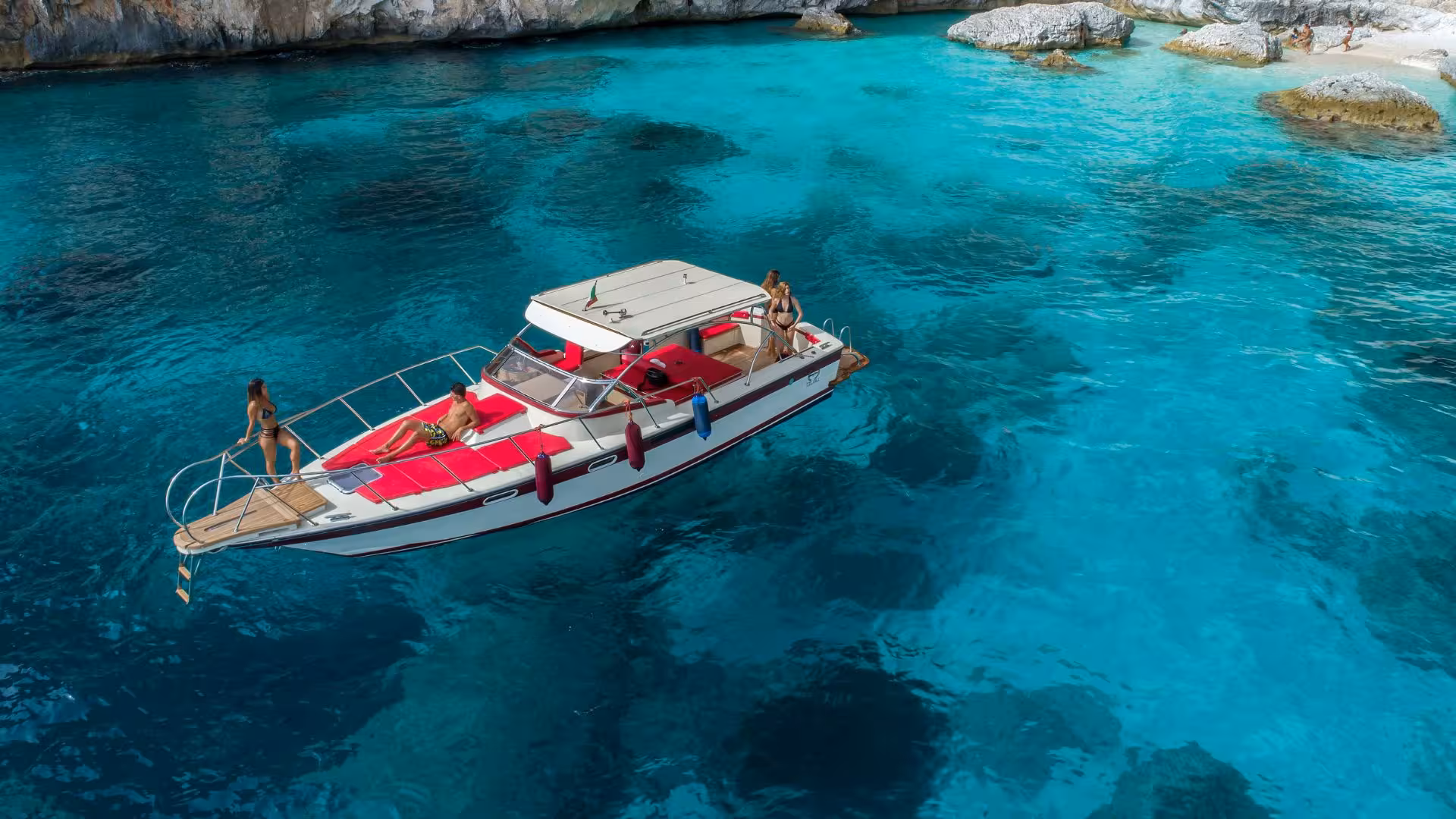 Tourists enjoying a boat excursion on crystal-clear waters near Cala Gonone in the Gulf of Orosei, Sardinia.
