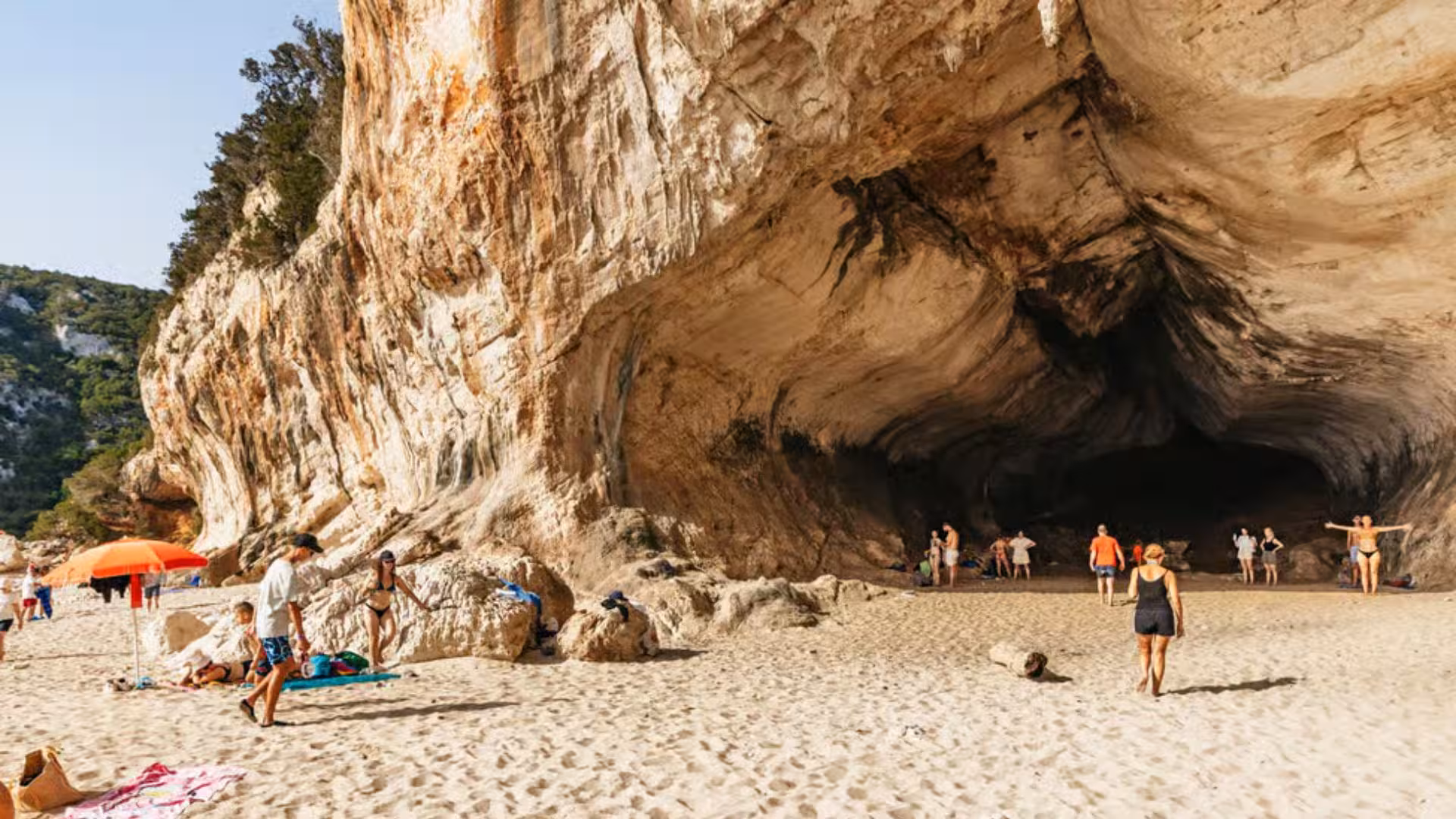 Visitors explore a stunning cave on a sandy beach during a dinghy tour in the Gulf of Orosei from Cala Gonone.