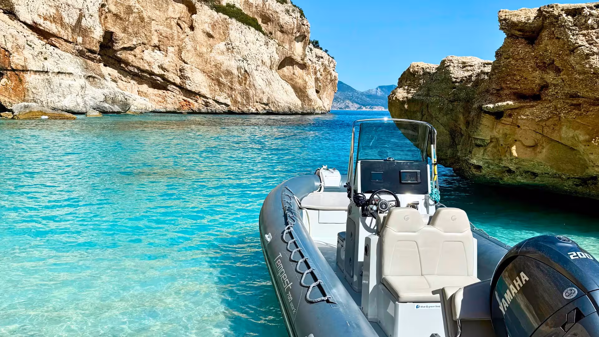 A dinghy floats on vibrant blue waters surrounded by rocky cliffs in the Gulf of Orosei, ideal for exploration from Cala Gonone.