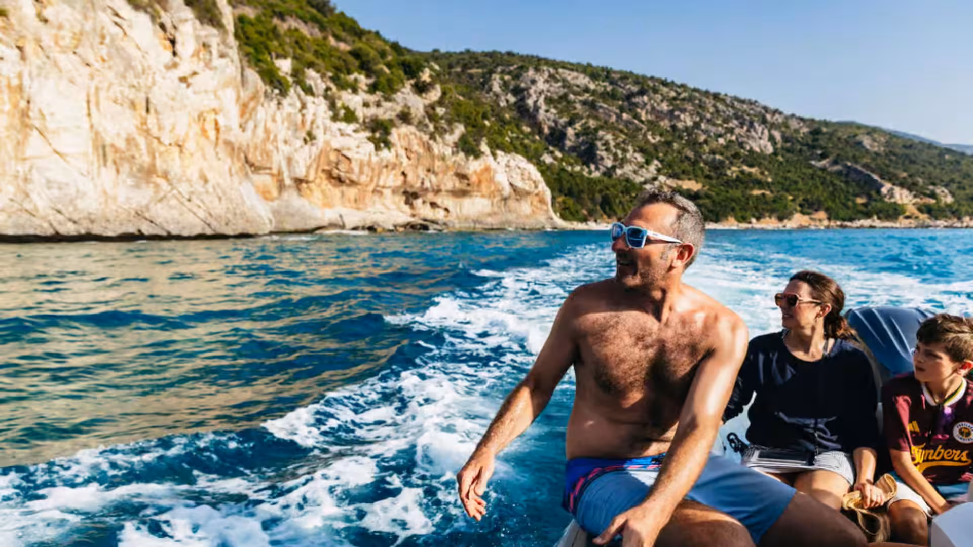 Family enjoys scenic views from a dinghy tour along the rugged coastline of the Gulf of Orosei near Cala Gonone.
