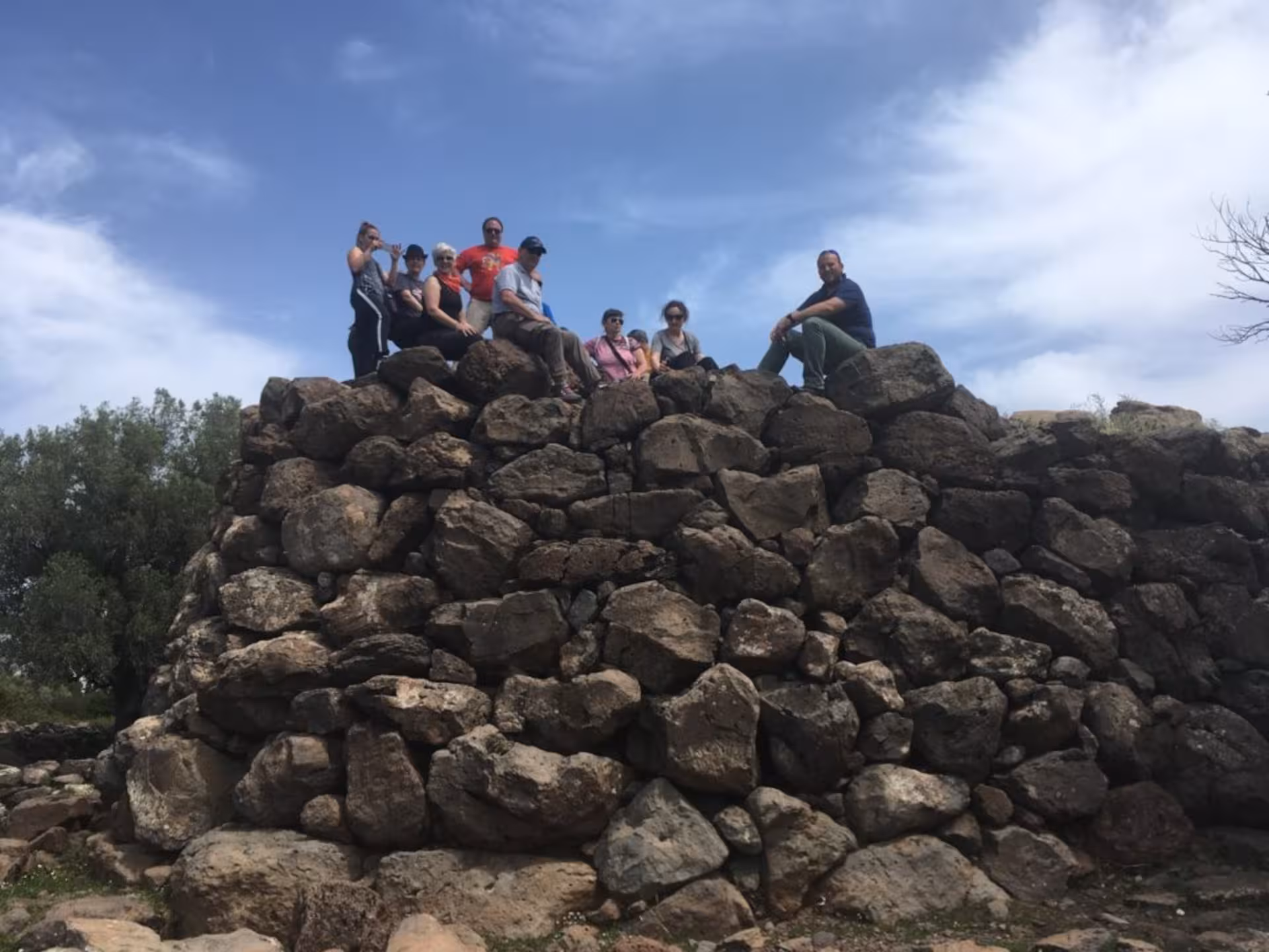Tour participants sit atop an ancient stone structure in Supramonte on a Jeep tour from Cala Gonone.