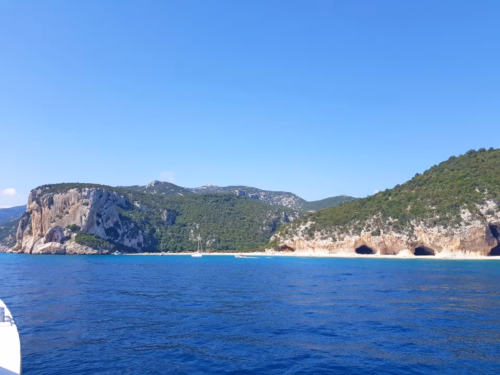 Scenic view of Bue Marino Caves against lush hills and clear blue sea, perfect for a Cala Gonone motorboat tour.