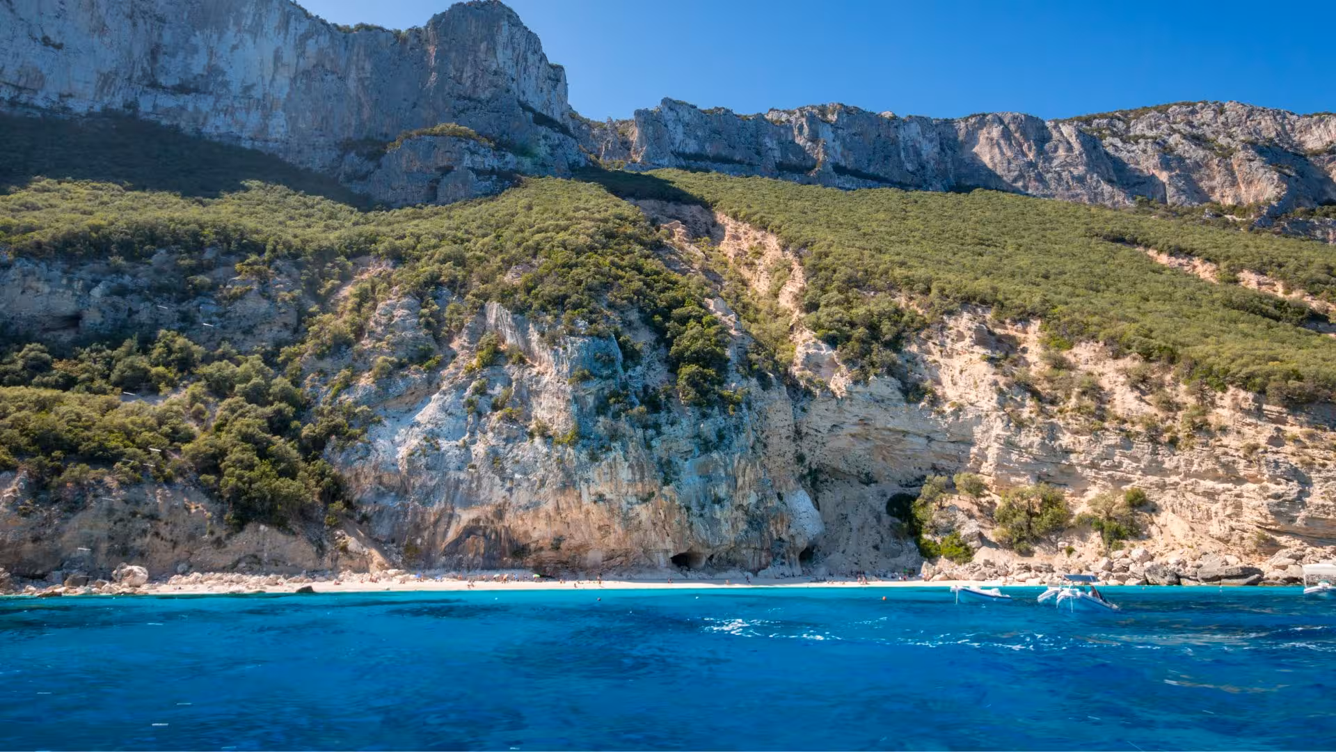 Dramatic cliffs and lush greenery overlooking the pristine waters of Cala Gonone, perfect for RIB adventures.