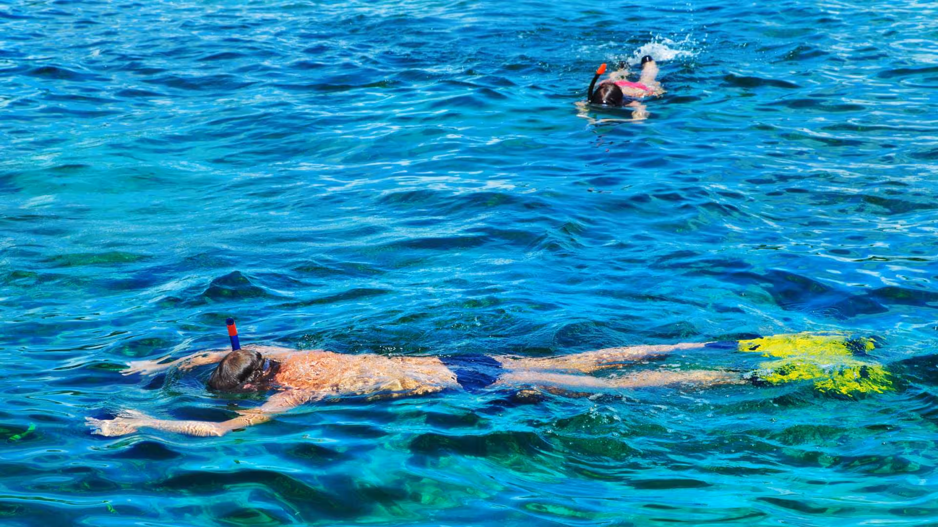 Two snorkelers exploring the crystal-clear waters of Cala Gonone in the Orosei Gulf, showcasing vibrant marine life.